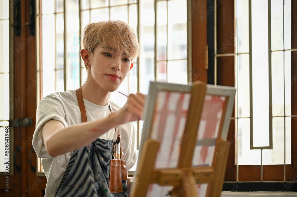 A creative and talented young Asian gay man artist painting his artwork on a canvas easel A creative and talented young Asian gay man artist painting his artwork on a canvas easel