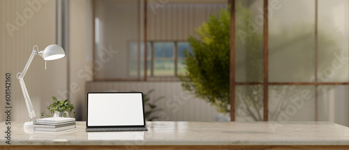 A tablet white screen mockup on a tabletop over blurred background of a minimal room. © bongkarn