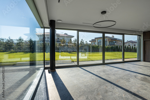 empty space of a room without furniture of a country house with large panoramic windows for renting real estate, a green lawn outside the window