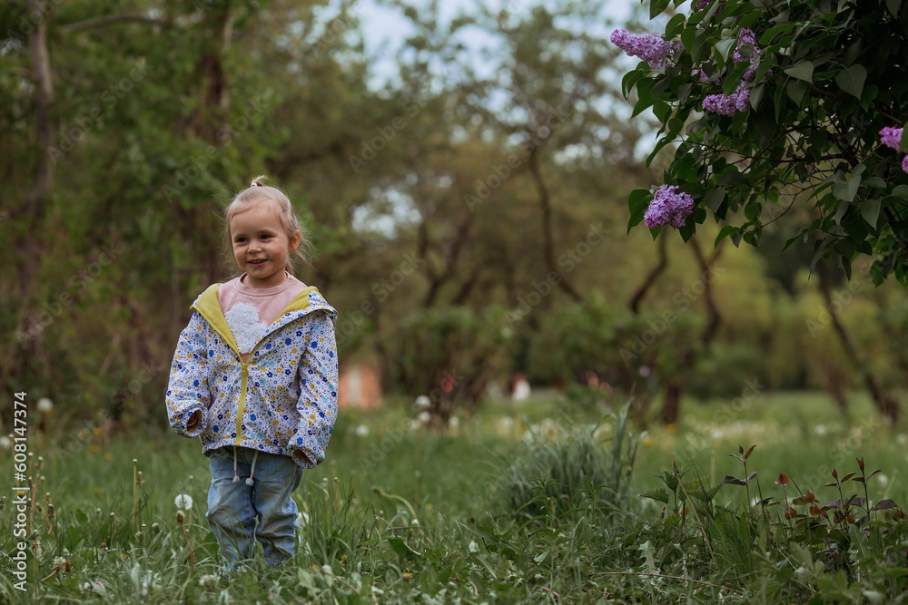 Portrait of a beautiful little girl 3 years old playing in nature . Childhood. The baby poses in the park on the green lawn.