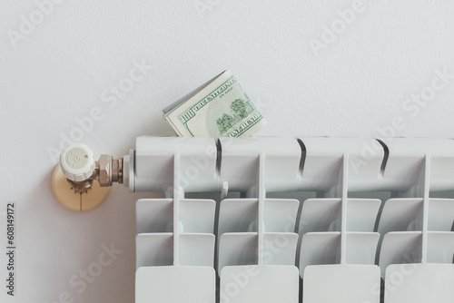 a stack of money dollars on a white battery heating radiator on a white wall  the concept of saving utility bills  Energy crisis