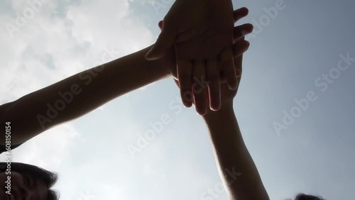 Successful team, many hands holding together on sky background in slow motion
