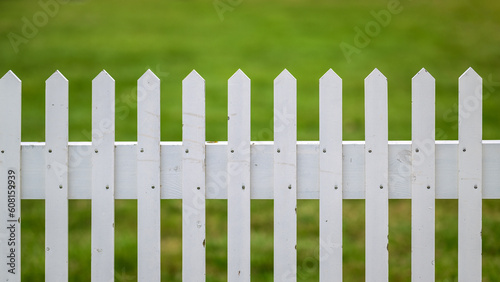 White rustic picket fence in front of green grass