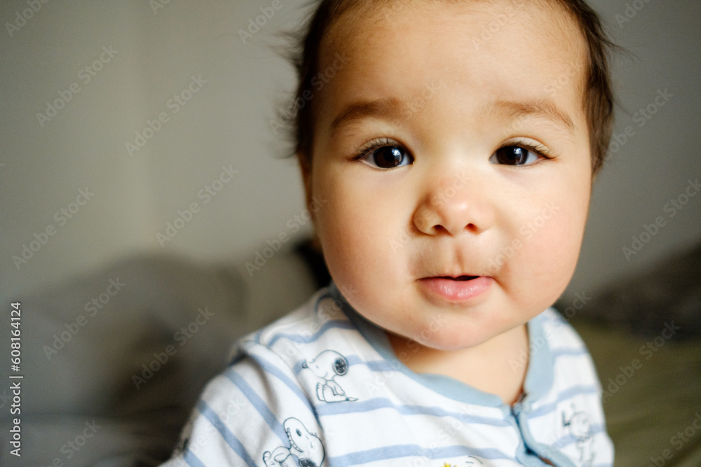 close up of baby latin american girl smiling in bedroom with soft natural light looking in camera. cute hispanic baby girl