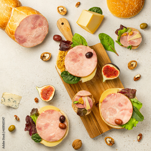 Mix of different snacks and appetizers. Space for text. Deli, sandwiches, olives, sausage, fig, cheese, Gorgonzola, walnut, Salad leaves on light stone backgrounds. Top view.