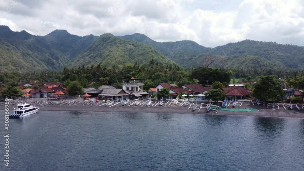 Lush tropical mountains and jukung fishing Boats on black sand beach in Amed Village, Bali - Indonesia, Aerial. Lush tropical mountains and jukung fishing Boats on black sand beach in Amed Village, Bali - Indonesia, Aerial.