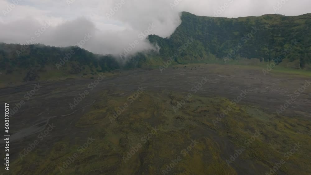 Aerial altitude view dive volcanic black sand lava low field wild mountain valley landscape cloudy sky. FPV sport drone low dynamic shot natural volcano scenery yellow dry grass plant area environment Aerial altitude view dive volcanic black sand lava low field wild mountain valley landscape cloudy sky. FPV sport drone low dynamic shot natural volcano scenery yellow dry grass plant area environment