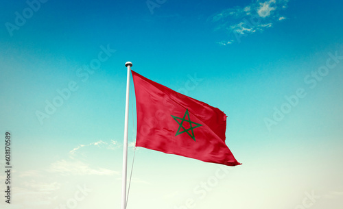 Waving Flag of Morocco in Blue Sky. The symbol of the state on wavy cotton fabric.