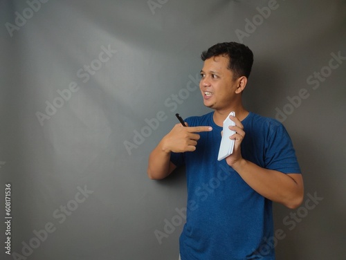 Young asian man shocked when he looking and pointing smartphone