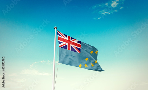 Waving Flag of Tuvalu in Blue Sky. The symbol of the state on wavy cotton fabric.