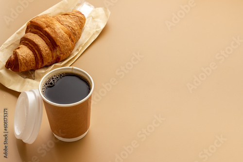 One disposible paper cup of coffee to go with croissant photo