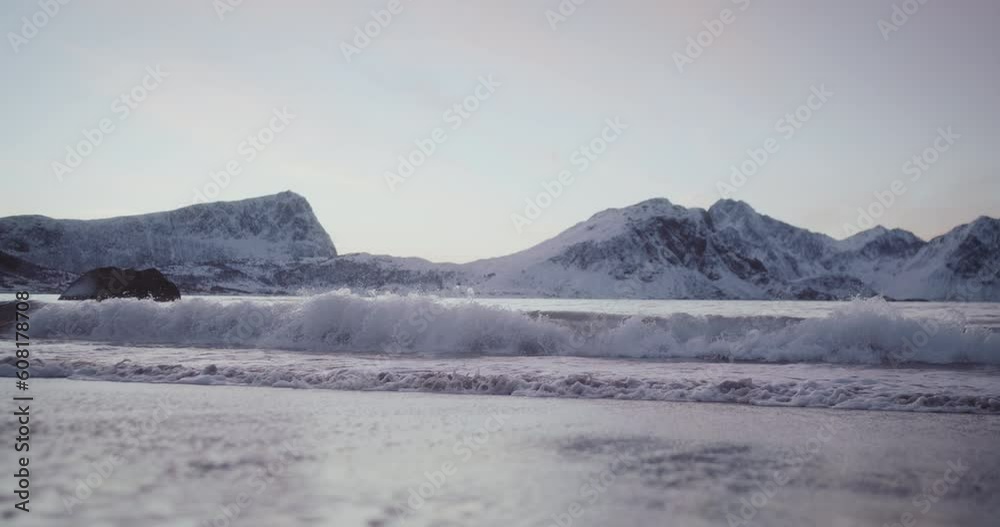 Waves splash on beach at Lofoten, Norway on sunny winter day Waves splash on beach at Lofoten, Norway on sunny winter day