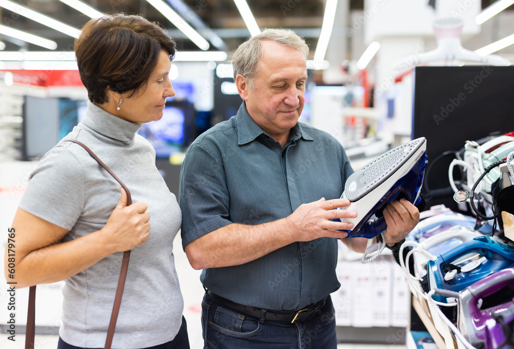 Fototapeta premium Older couple picking out new clothes iron to buy in electronics department of supermarket