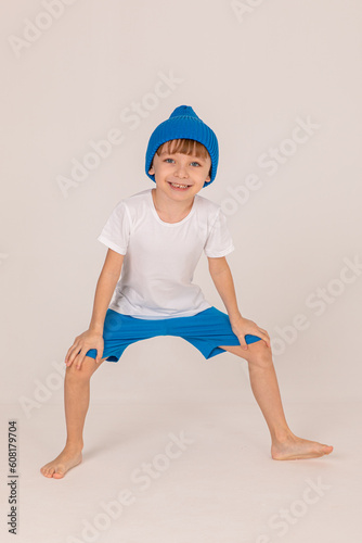 Happy, funny, little boy in a blue clothes on white background. Blue knitted hat on the head of child. Kids, children having fun on ski resort