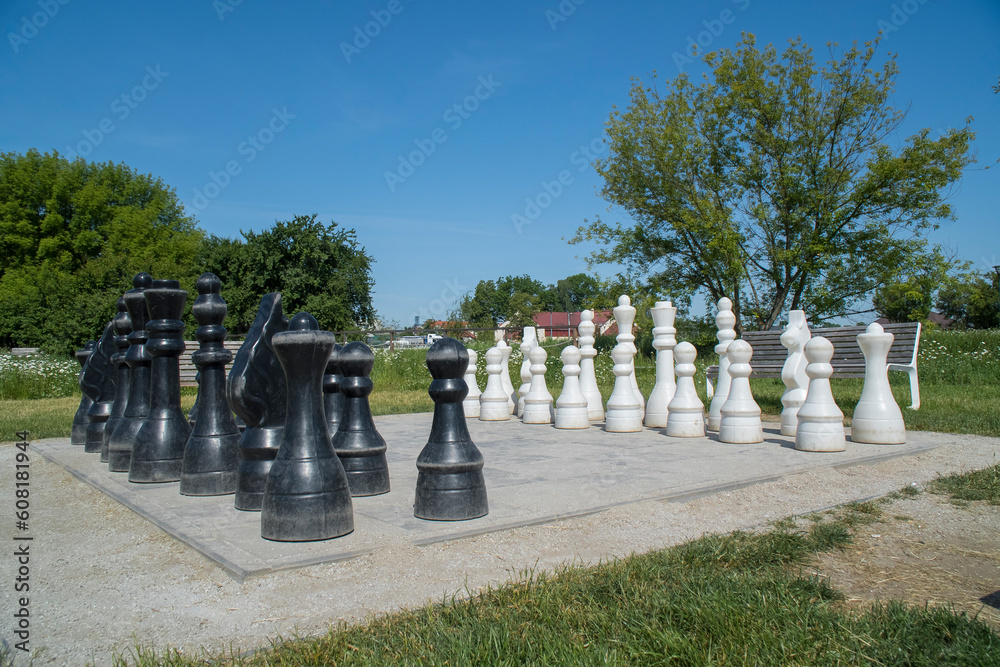 Szachownica z szachami w parku pośród zieleni. Duże szachy. - obrazy, fototapety, plakaty 