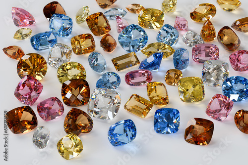 Variously cut, colored topaz stones scattered on white background.