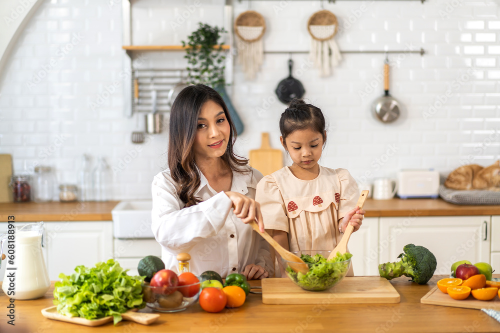 Portrait of enjoy happy love asian family mother with little asian girl daughter child having fun help cooking food healthy eat together with fresh vegetable salad ingredient in kitchen