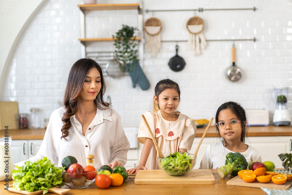 Portrait of enjoy happy love asian family mother with little asian girl daughter child having fun help cooking food healthy eat together with fresh vegetable salad ingredient in kitchen