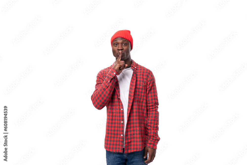 handsome joyful dark-skinned man in a casual plaid shirt keeps a secret on a white background with copy space