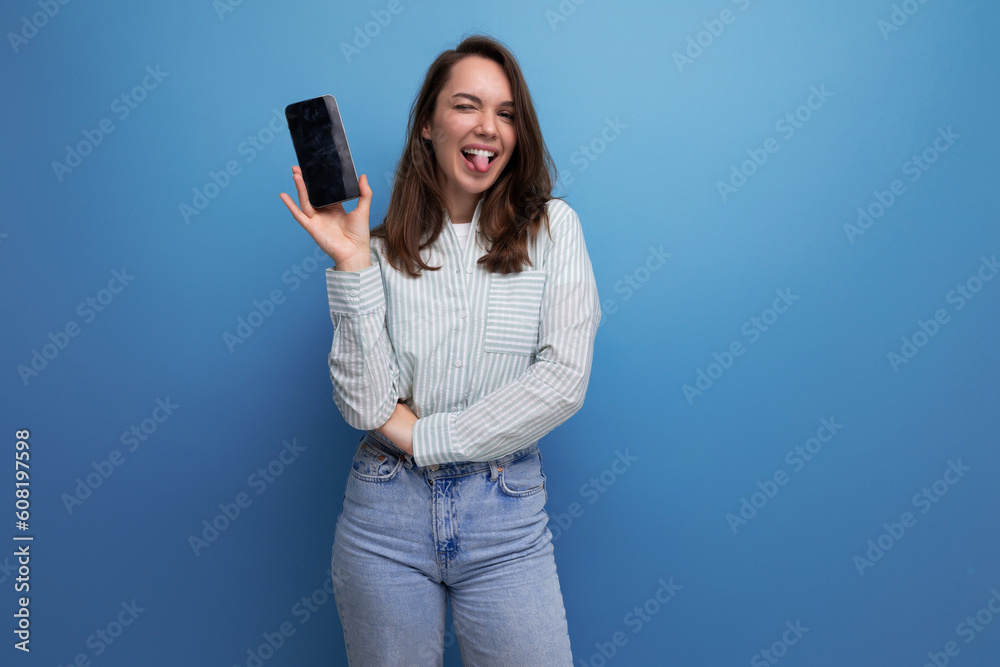 pretty young brunette lady dressed in a striped shirt and jeans with a smartphone in her hands pretty young brunette lady dressed in a striped shirt and jeans with a smartphone in her hands