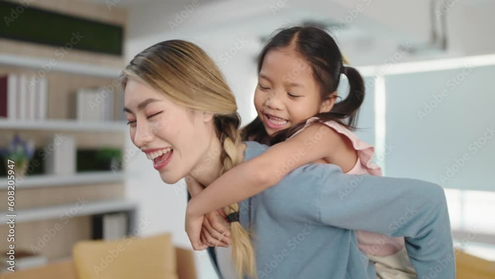 Cheerful and happy asian little daughter riding on mother's back. Mom and child spend time together on holidays. Mother's Day love family concept Cheerful and happy asian little daughter riding on mother's back. Mom and child spend time together on holidays. Mother's Day love family concept