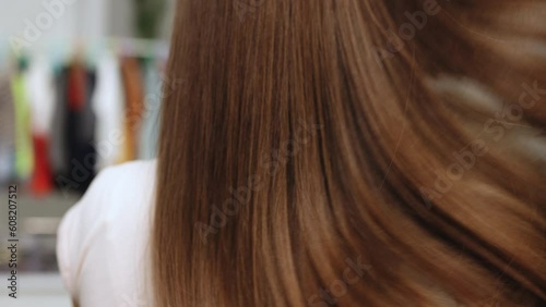 Sexy brunette Model girl with Healthy Hair. Woman moves long hair. Rear view. Girl shakes long straight hair. Female model is fluttering hair. Beauty woman with luxurious straight brown hair