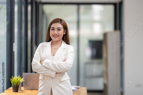 Shot of businesswoman standing front of her table in office. Smile and look at camera.