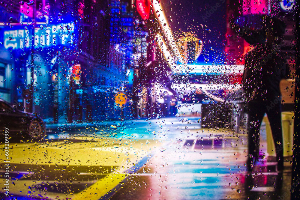 iew through glass window with rain drops on blurred reflection silhouette of a girl on a city street after rain and colorful neon bokeh city lights, night street scene. Focus on raindrops on glass	