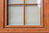 Zbliżenie na szybę w oknie z brązową ramą okienną
