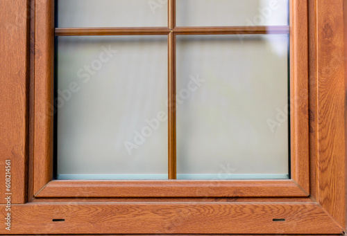 Zbliżenie na szybę w oknie z brązową ramą okienną