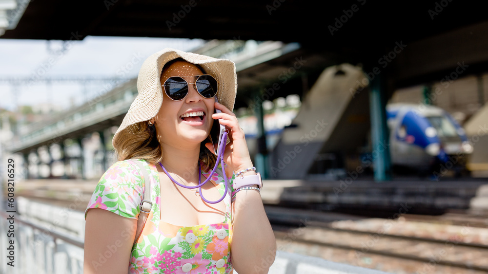 Happy tourist at the train station using your smartphone