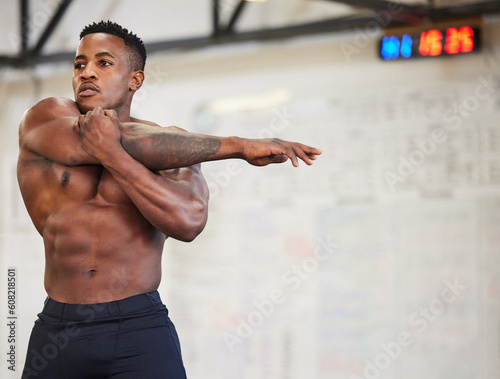 Shirtless black man, stretching arms and fitness in gym with muscle, strong and abs with workout and mockup space. Focus, serious male athlete and bodybuilder, warm up and ready for exercise