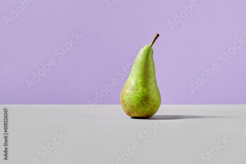 Green pear on a gray-violet background. Stylish vegan concept