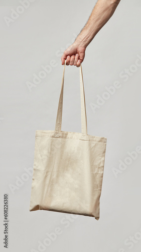 Cloth bag in hand on light background. Bag shoper in the hand