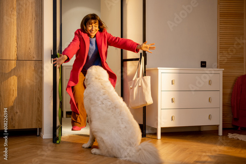 Fotografia Dog meets its owner at the doorway of living room at home