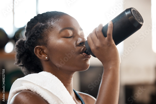 Black woman, fitness and drinking water at gym for sustainability, hydration or thirst after workout exercise. Thirsty African female person with drink for refreshment after cardio training indoors