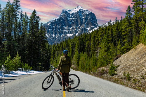 Woman cyclist on the track. Road to the mountains. Trail into the mountains and into the forest. Banff National Park.