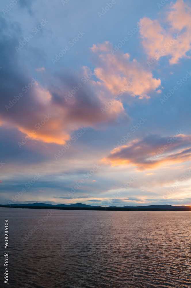 Summer sunset landscape with dramatic clouds - rippled water surface lit by sunset summer light