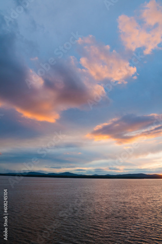 Summer sunset landscape with dramatic clouds - rippled water surface lit by sunset summer light