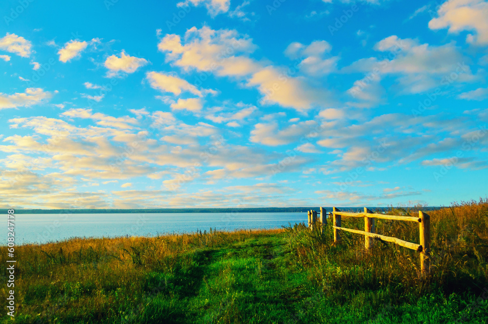 Fototapeta premium Summer landscape, field pathway along the lake, dramatic colorful sunset sky