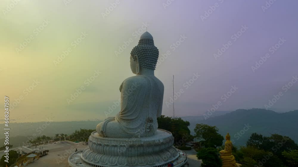 Aerial hyperlapse view of the sun shining through the fog covering Phuket big Buddha..Fog around Phuket big Buddha at a sweet sunrise..The beauty of the statue fits perfectly with the charming nature