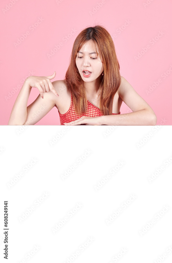 Young Asian woman is standing behind the white blank banner or empty copy space advertisement board on isolated background. Young Asian woman is standing behind the white blank banner or empty copy space advertisement board on isolated background.