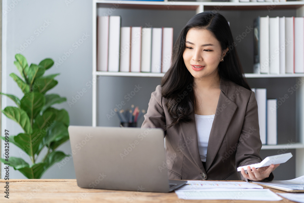 Businesswoman using laptop for doing financial mathematics on wooden table in business office, statistics and analytical research concept, accounting, tax Businesswoman using laptop for doing financial mathematics on wooden table in business office, statistics and analytical research concept, accounting, tax