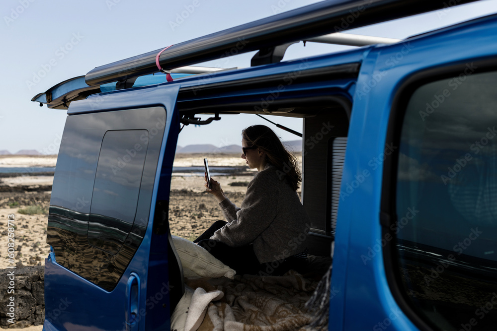 Anonymous woman browsing smartphone in camper van Anonymous woman browsing smartphone in camper van