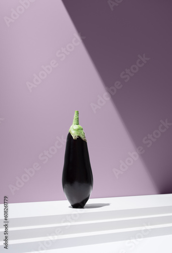 Black eggplant mounted on white surface against purple background photo