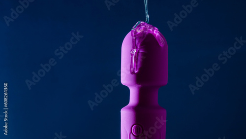 Canvas Print Intimate lubricant pours on a purple vibrator on a blue background