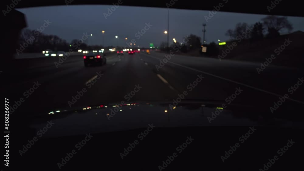 Background plate of night time POV point of view of traffic and city lights from car hood and driver perspective moving towards downtown district out of focus