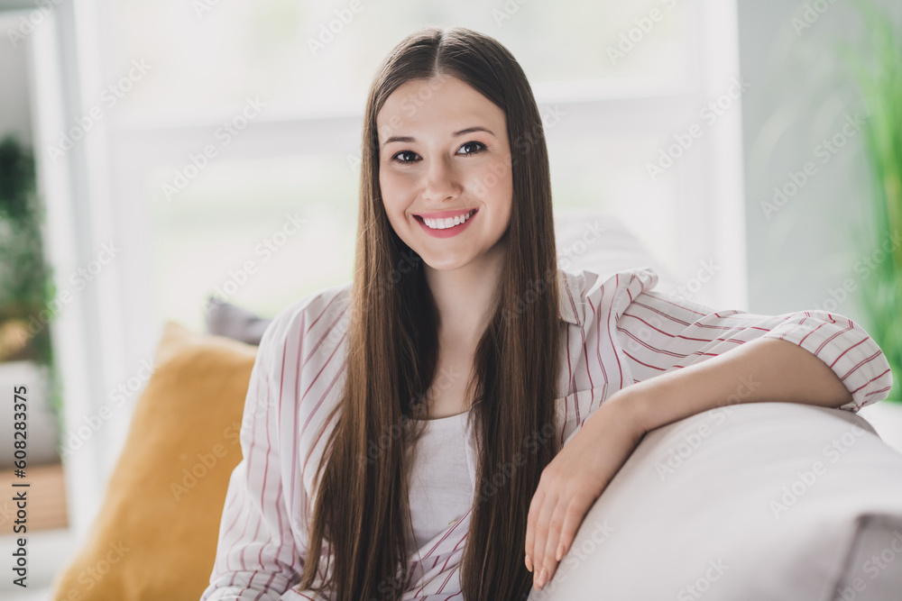 Photo of adorable dreamy young lady dressed striped shirt sitting couch smiling indoors house room Photo of adorable dreamy young lady dressed striped shirt sitting couch smiling indoors house room