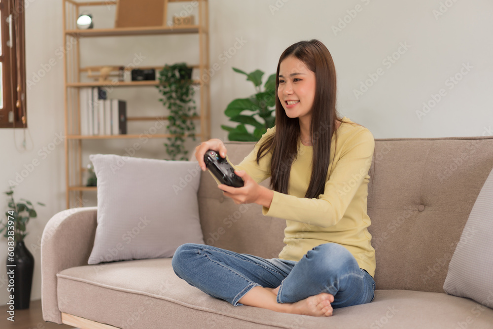 Relaxation concept, Young woman sitting on the couch to control joystick while playing video games Relaxation concept, Young woman sitting on the couch to control joystick while playing video games