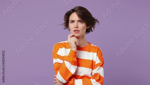 Puzzled young woman wear casual clothes look aside put hand prop up on chin iterates over solution options feels doubtful thinks but no decision comes isolated on plain pastel light purple background